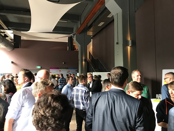 Mitarbeiter stehen in einer Halle an ständen 